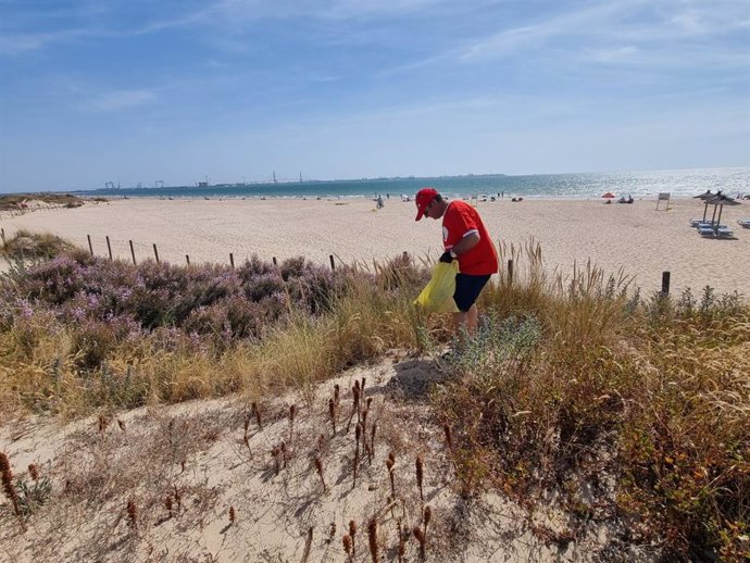 Un voluntario en la jornada de recogida de residuos en la playa de Valdelagrana en El Puerto de Santa María (Cádiz)