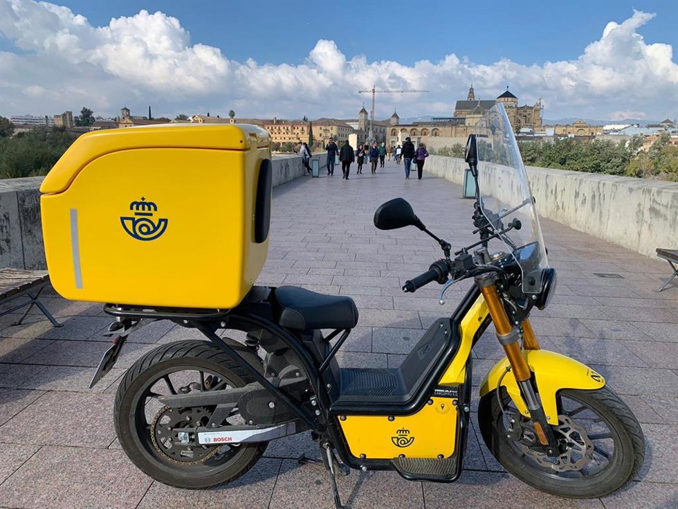Archivo - Una moto eléctrica de reparto de Correos en el Puente Romano de Córdoba.