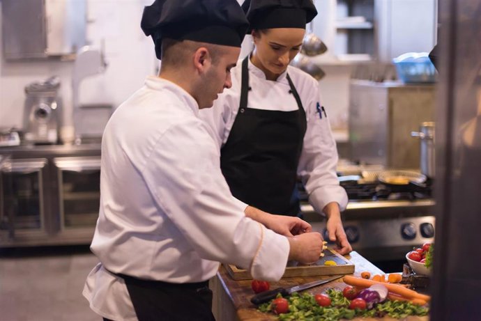 Archivo - Dos profesionales trabajan en una cocina.