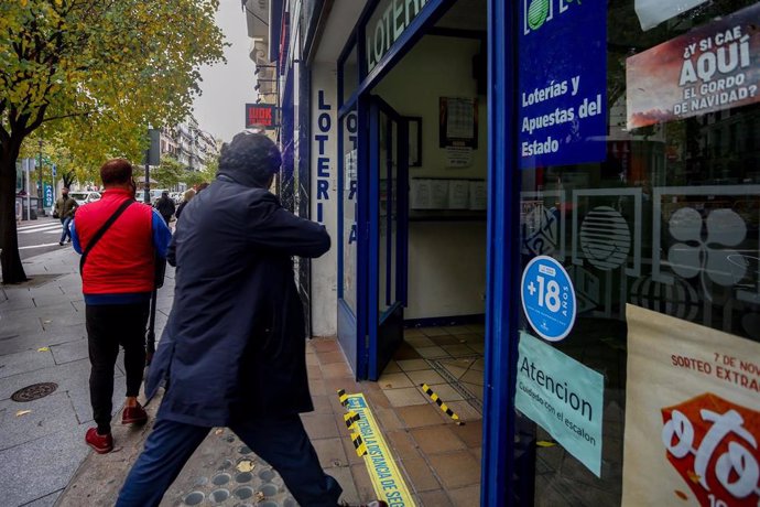 Archivo - Una persona entra por la puerta de la administración de lotería Doña Manolita donde se venden boletos para el Sorteo Extraordinario de la Lotería de Navidad 2020, Madrid. (Foto de archivo).