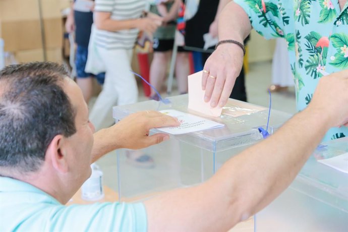Archivo - Una dona diposita el seu vot en un col·legi electoral