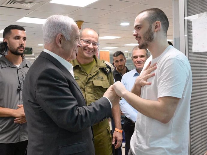 El primer ministro israelí, Benjamin Netanyahu (I), habla con el rehén ruso-israelí Andrey Kozlov tras su rescate por el Ejército israelí de su cautiverio en la Franja de Gaza