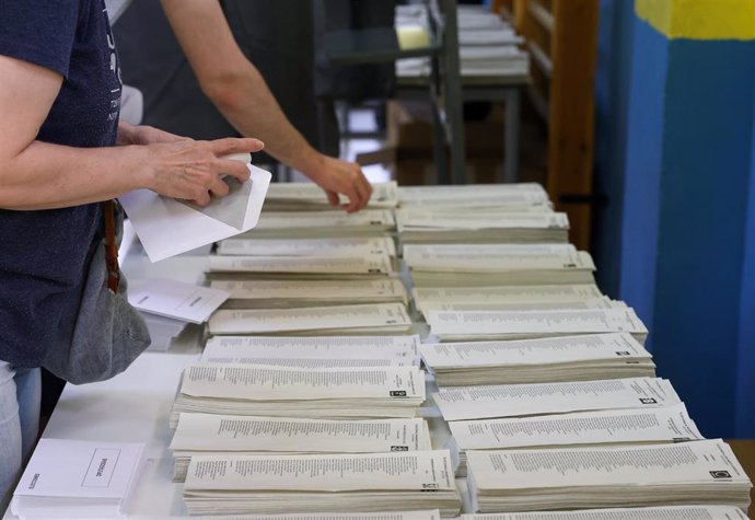 Varias personas ejercen su derecho a voto en un colegio público.