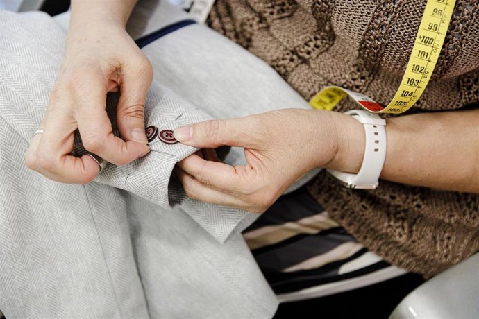 Archivo - Una modista cose un botón en la manga de un traje de comunión en la tienda especializada 
