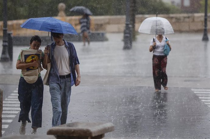Archivo - Varias personas con paraguas bajo la lluvia