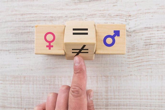 Concepts of gender equality. Hand flip wooden cube with unequal symbol changing to equal sign