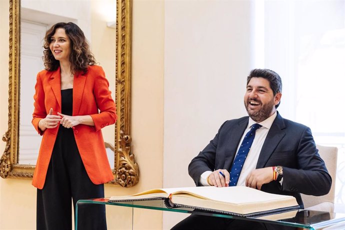 La presidenta de la Comunidad de Madrid, Isabel Díaz Ayuso y el presidente de la Región de Murcia, Fernando López Miras, que escribe en el libro de firmas de la Real Casa de Correos, a 11 de junio de 2024, en Madrid (España).