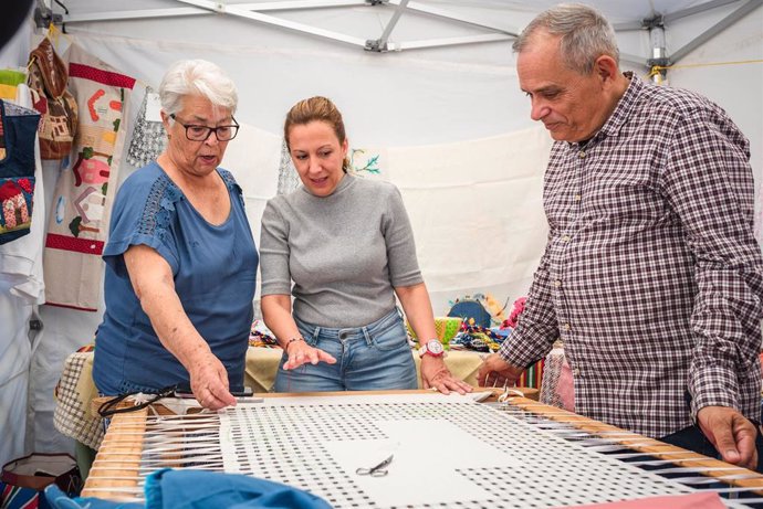 La presidenta del Cabildo de Tenerife, Rosa Dávila, y el consejero de Empleo y Educación, Efraín Medina, visitan un stand en una feria de artesanía