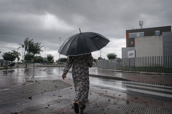 Archivo - Una mujer camina bajo la lluvia