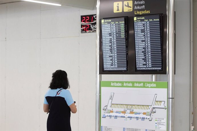 Archivo - Una pasajera observa la pantalla del aeropuerto de Palma.