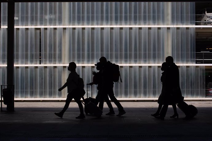 Archivo - Varias personas caminan con su equipaje en el Aeropuerto de Barcelona