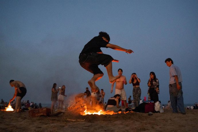 Archivo - Una persona salta una hoguera durante la noche de San Juan