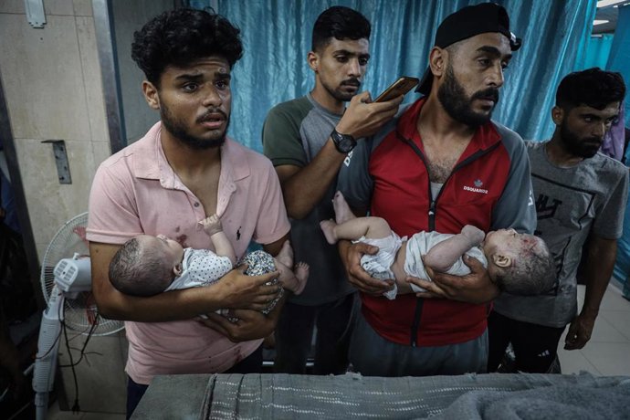 Dos personas sostienen a dos bebés que resultaron heridos cuando llegaban al Hospital de los Mártires de Al-Aqsa como resultado de un bombardeo israelí en Al-Hasaniyah. en el campo de Nuseirat, en el centro de la Franja de Gaza.
