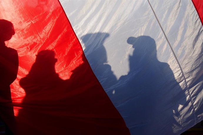 Archivo - Bandera de Perú sostenida por manifestantes durante una marcha en Lima