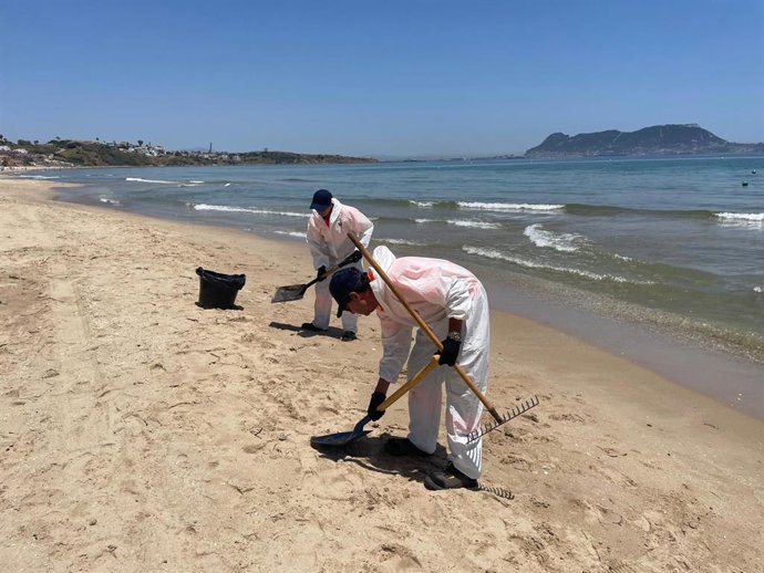 Personal del servicio de limpieza y mantenimiento de playas de Algeciras retira el vertido de fuel de la playa de Getares.