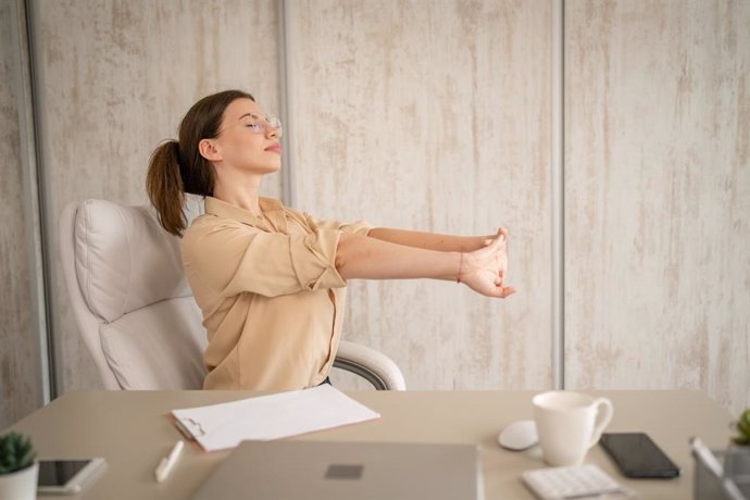 Archivo - Mujer haciendo ejercicio de estiramentos en el trabajo.