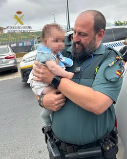 Agente de la Guardia Civil de Lepe (Huelva) con el bebé rescatado en brazos.