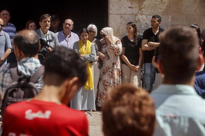 Varias personas se abrazan durante un minuto de silencio por el fallecimiento de un niño de once años ahogado el pasado jueves, 13 de junio, en el río Júcar