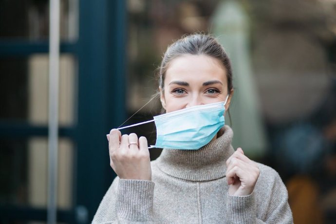 Archivo - Mujer quitándose la mascarilla.