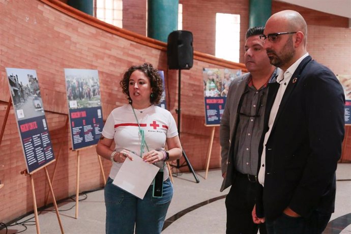 Voluntaria de Cruz Roja junto al presidente de la entidad en Extremadura, Jesús Palo, y el concejal de Cooperación, Ángel Calle, visitan las exposición.