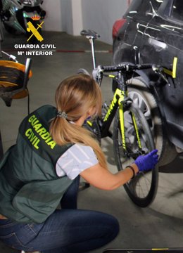 Una agente de la Guardia Civil junto a la bicicleta y el coche implicados