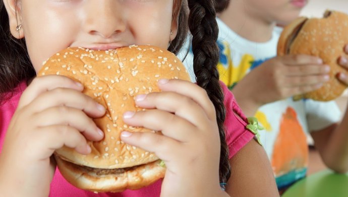 Archivo - Imagen de archivo de una niña comiendo una hamburguesa.