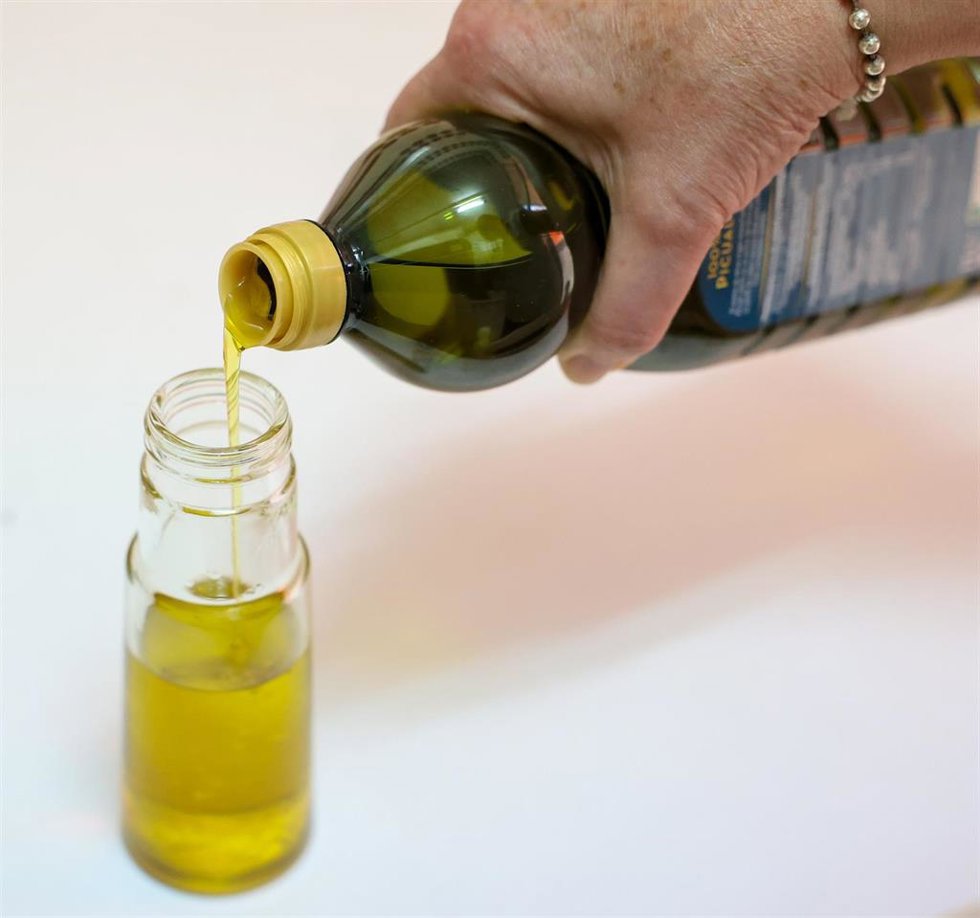 Una persona llena un bote de aceite de oliva.