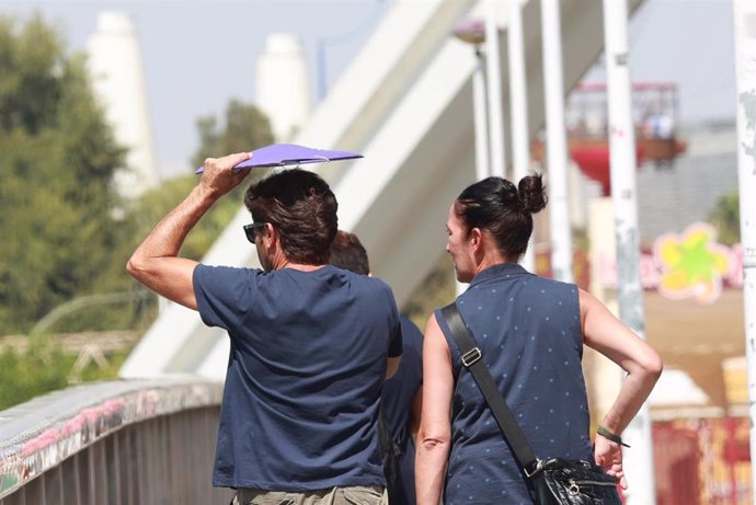 Archivo - Un hombre cruza el puente de la Barqueta usando una carpeta para protegerse de las altas temperaturas, a 24 de agosto en Sevilla (Andalucía, España). 