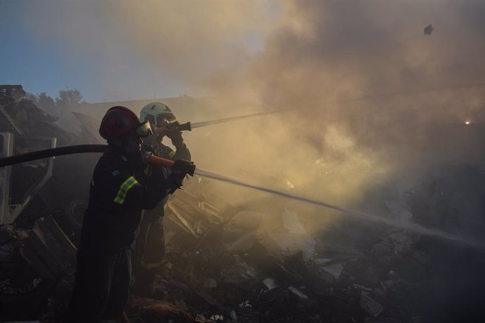 June 19, 2024, Koropi, Eastern Attica, Greece: Firefighters attempt to extinguish a fire amidst thick smoke that has broke out in a factory area during a wildfire in the eastern suburbs of the Greek capital. Authorities have urged residents to evacuate an