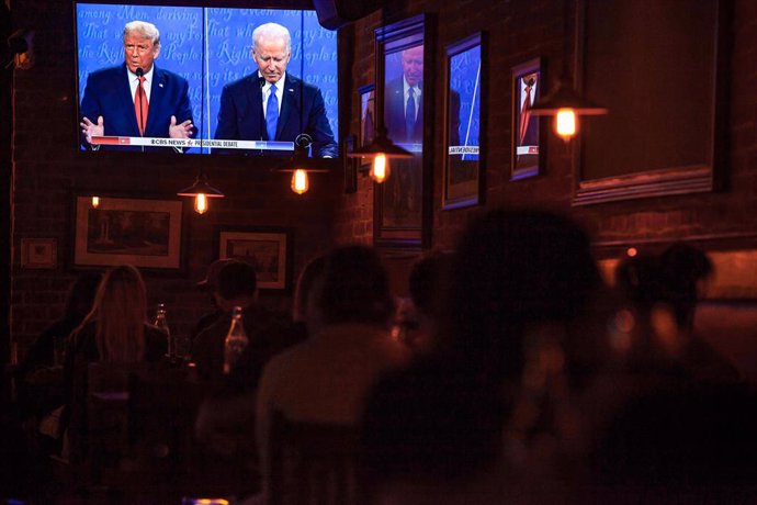 Archivo - 22 October 2020, US, Columbus: People watch US President Donald Trump (L) and Former Vice President and Democratic Presidential candidate Joe Biden, speak on a big screen TV at Oddfellows Liquor Bar during the final presidential debate. Photo: S