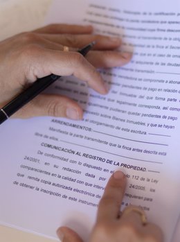 Archivo - Una mujer con un bolígrafo, señala una escritura de compraventa de una hipoteca.