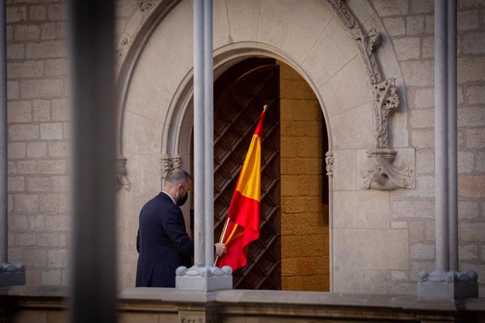 Archivo - Un hombre retira la bandera de España antes de que el president de la Generalitat comparezca en rueda de prensa en el Palau de la Generalitat, previo a la segunda reunión de la mesa del diálogo entre el Gobierno central y el Govern catalán, a 15