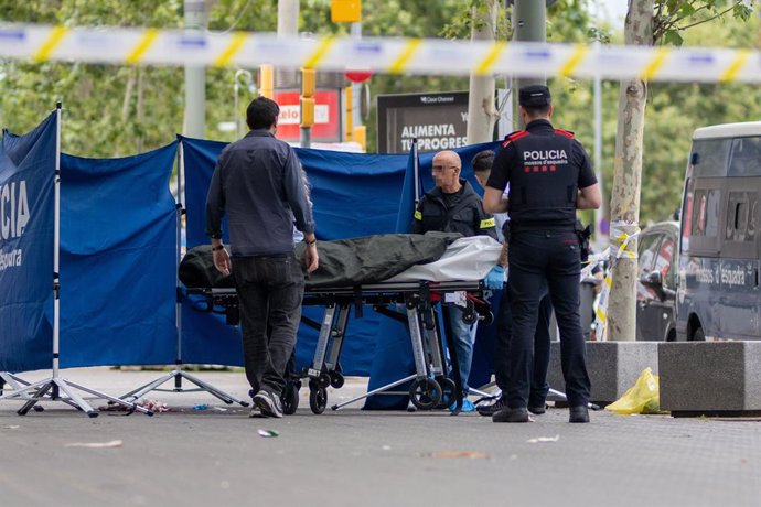 Agents dels Mossos d'Esquadra i treballadors de la funerària aixequen el cadàver del jove mort, al passeig Joan de Borbó, a 24 de juny del 2024, a Barcelona, Catalunya