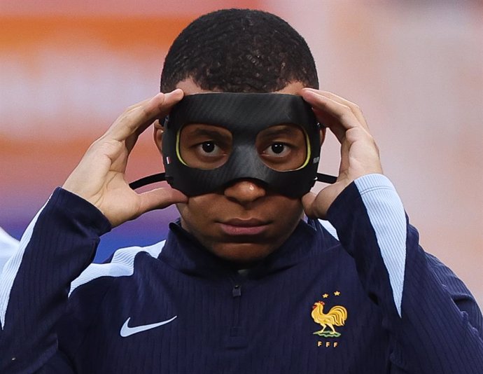 21 June 2024, Saxony, Leipzig: France's Kylian Mbappe warms up with a protective mask after breaking his nose before the UEFA Euro 2024 Group D soccer match between Netherlands and France at Leipzig Stadium. Photo: Jan Woitas/dpa