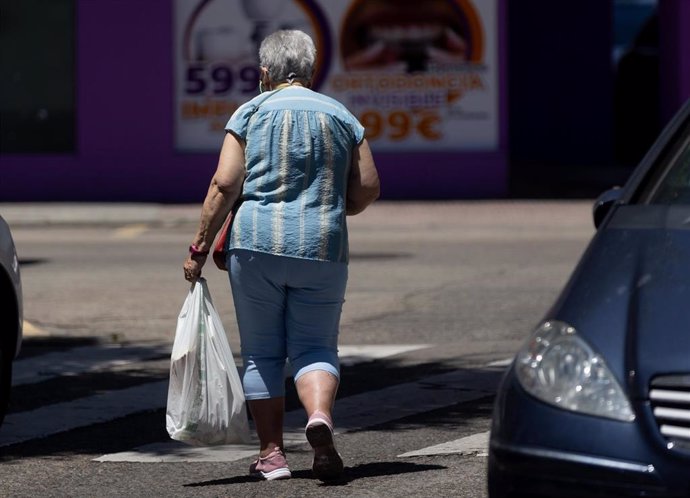 Una señora mayor sujeta una bolsa mientras camina, a 24 de junio de 2024 