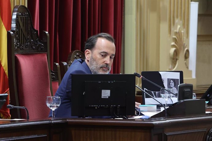 El presidente del Parlament, Gabriel Le Senne, junto a la impresión rota de los retratos de las 'rojas del Molinar'.