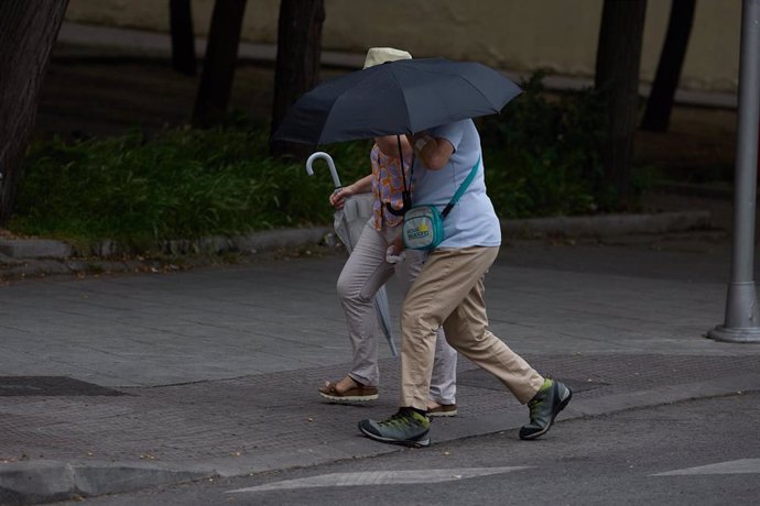 Dos personas se protegen de la lluvia con un paraguas, a 8 de junio de 2024, en Madrid (España). 