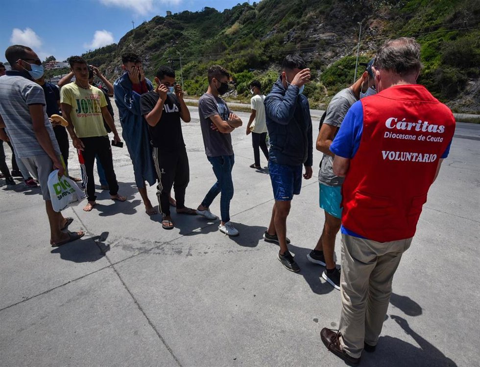 Archivo - Un trabajador de Cáritas Diocesana reparte alimentos a migrantes que entraron a Ceuta hace 3 semanas, a 7 de junio de 2021, en Ceuta, (España). 