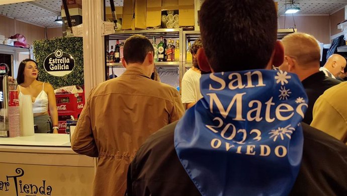 Archivo - Un ovetense luce el pañuelo de las fiestas de San Mateo 2023 mientras espera a ser atendido en una de las casetas hosteleras ubicadas en la Plaza Porlier.