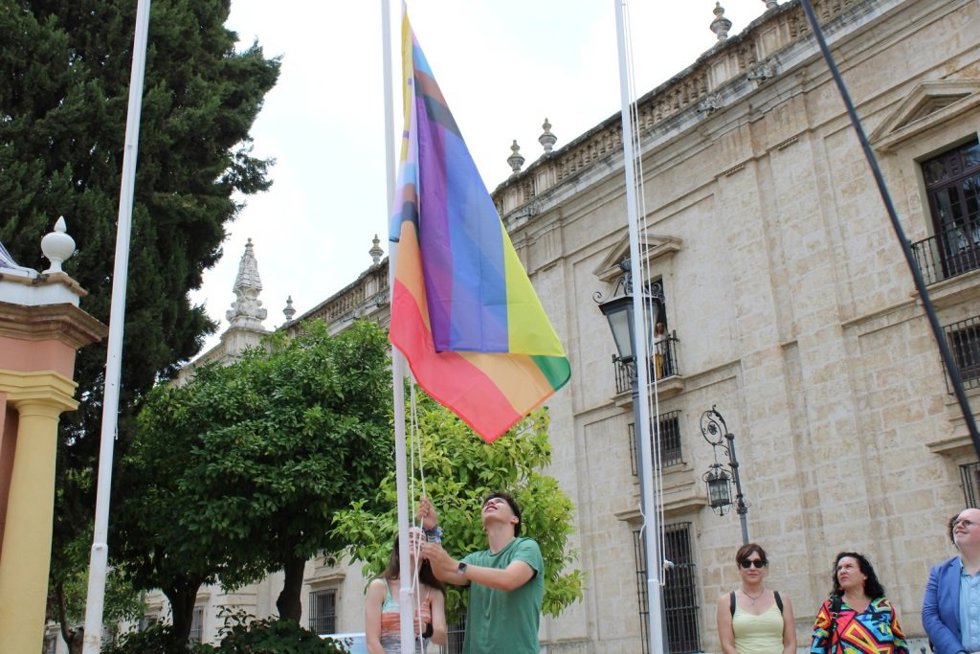 Un alumno de la Universidad de Sevilla (US) iza la bandera de Lgtbiqa+ en el Rectorado.