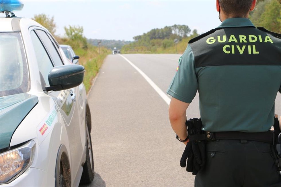 Agente de la Guardia Civil junto a un vehículo oficial.