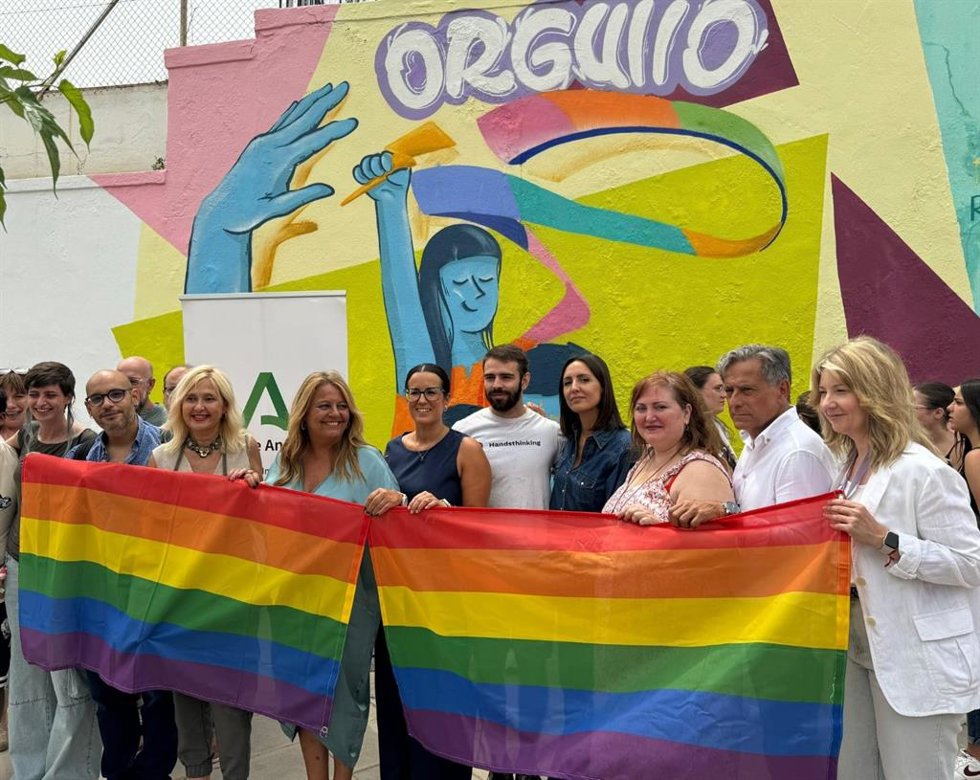 Asistentes al acto con motivo del Día Internacional del Orgullo Lgtbi, con el grafiti colaborativo detrás.