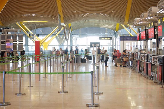 Archivo - Un grupo de personas esperan en uno de los pasillos de facturación de la Terminal T4 del Aeropuerto Adolfo Suárez-Madrid Barajas con motivo de la operación salida de inicios de agosto, a 28 de julio de 2023, en Madrid (España) 