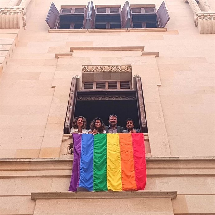Diputados de MÉS per Mallorca, junto a una bandera LGTBI desplegada en el Parlament.
