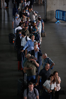Archivo - Varias personas esperan la cola de los taxis en la terminal de un aeropuerto.