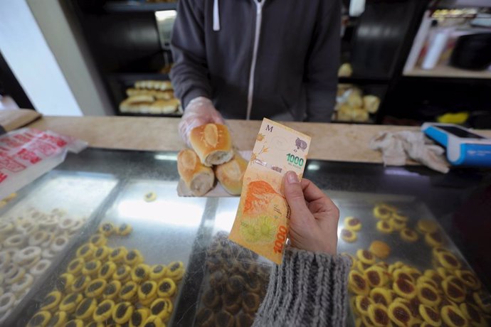 Archivo - 10 August 2022, Argentina, Buenos Aires: A woman pays with a 1000 peso bill at a bakery, as inflation rate in Argentina rises to 71 percent.