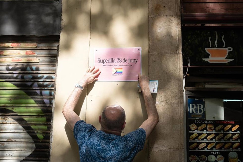 El presidente del Observatori contra la LGTBIfobia, Eugeni Rodríguez, cuelga un cartel en una pared de la 'supermanzana' de Sant Antoni.