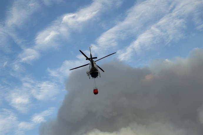 Archivo - Un helicóptero entre una columna de humo, en una imagen de archivo