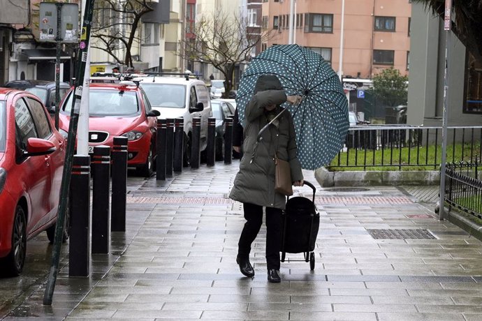 Archivo - Una mujer se refugia del viento con paraguas, a 8 de febrero de 2024, en A Coruña, Galicia (España).