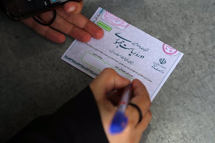 28 June 2024, Iran, Shahre Ray: An Iranian woman fills out her ballot during Iran's 2024 early Presidential elections at Shah Abdol-Azim Shrine polling station in Shahre Ray, southern Tehran. Following the helicopter crash that claimed the life of conserv